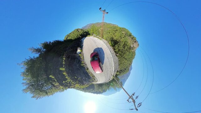 360 rotation Red Car on a Gravel Road Surrounded by Dense Green Trees and Clear Blue Sky, Captured in a Tiny Planet Effect with the Sun Shining Brightly Overhead