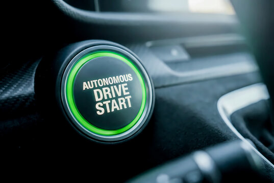 Close-up of an illuminated green autonomous drive start button on a modern car dashboard