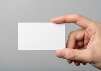 Obraz premium A hand holding a blank white business card against a simple neutral light gray background scene