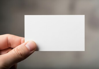Obraz premium A close up view of a person holding a blank white business card against a soft grey background.