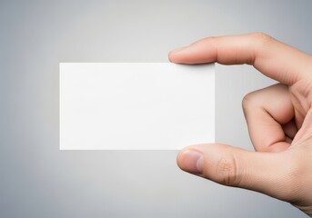 Obraz premium A close up view of a human hand holding a blank white rectangular business card for branding design