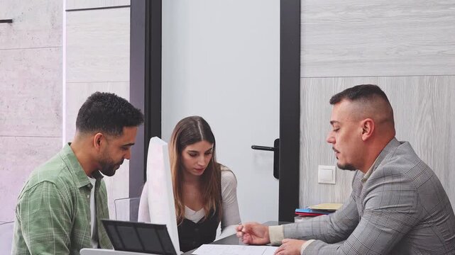 Professional male financial advisor consulting a young interracial couple. Clients meeting with a bank manager to discuss a mortgage loan