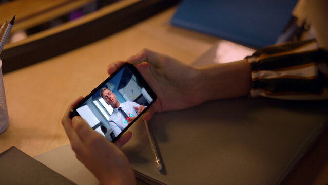 Office manager video calling cellphone having online interview at desk close up.