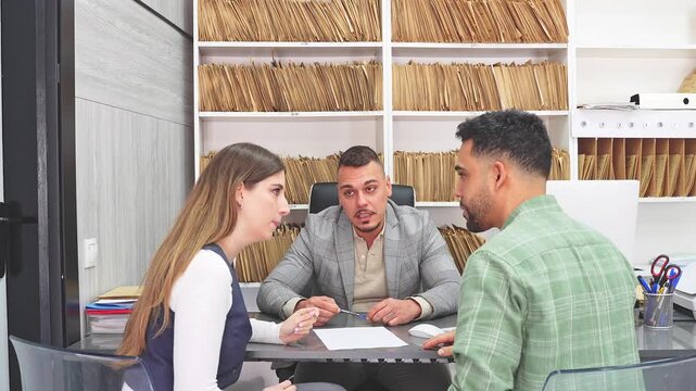 Displeased young couple arguing during a consultation. A male financial advisor tries to mediate the conflict in his office
