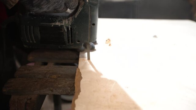 A close-up of a power saw sifts through a wooden surface.