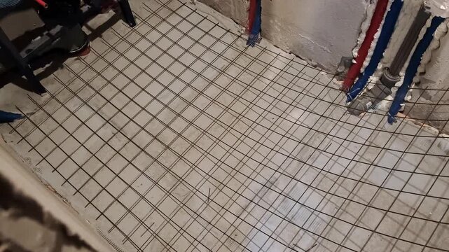 Worker prepares rebar wire mesh for concrete floor reinforcement. Indoor repair. House renovation. High quality 4k footage.
