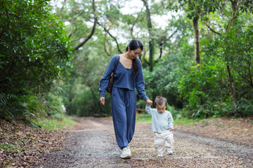 Fototapeta premium Mother with baby hiking in green forest area