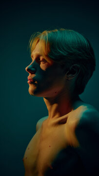 Side profile portrait of young man with clean skin in dramatic colored lighting. Concept of male skincare routine, daily care habits, hydration balance, and modern grooming lifestyle visuals.