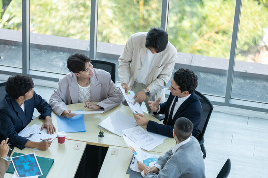 Top view of diverse business team meeting in office, analyzing charts and documents, collaborative teamwork, corporate strategy planning, data discussion, professional workspace, productivity concept