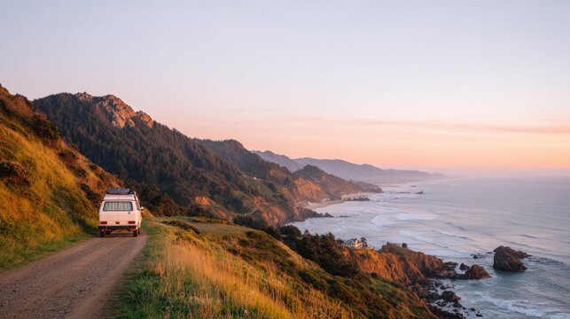 A vintage van parked on a winding coastal road with stunning mountains and ocean views at sunset