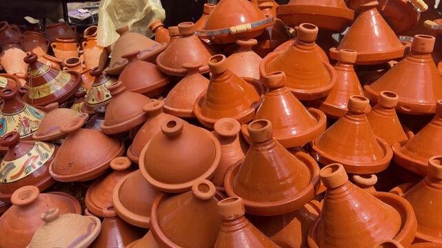 Traditional moroccan tajine pots displayed at a local market in Marrakesh. Many handmade clay tagines with colorful patterns and plain terracotta finish. Authentic pottery souvenirs in Morocco.