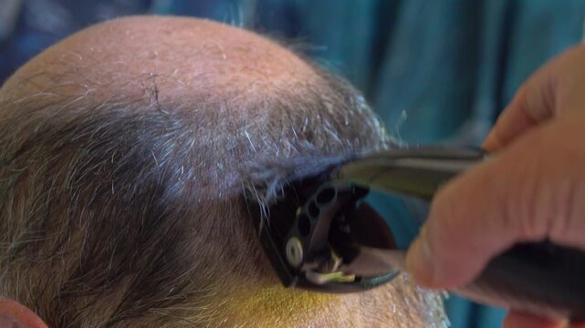 Person cuts hair of bald man at home