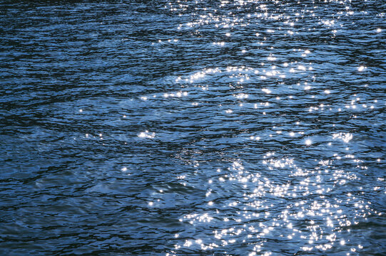 Sparkling blue water surface with sunlight reflecting on gentle ripples
