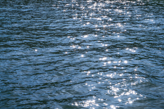 Sparkling blue water surface with sunlight reflecting on gentle ripples