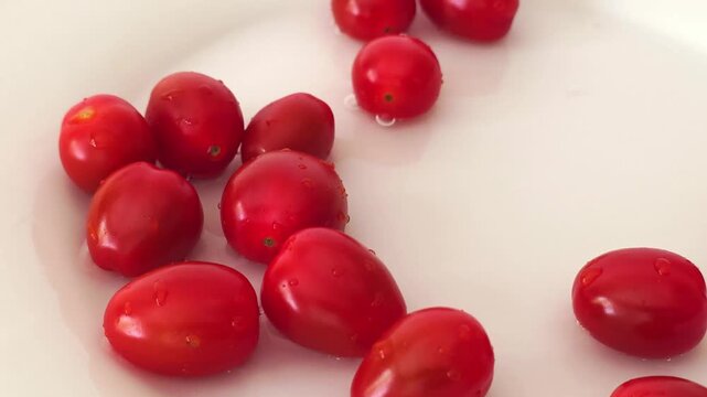 cherry tomatoes drops into water and makes splashes