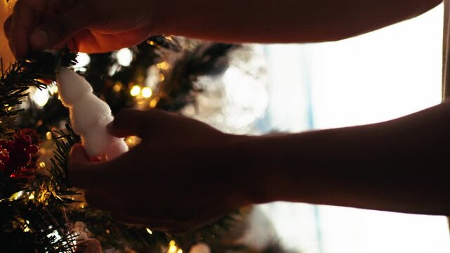 Person decorating christmas tree with white ornament