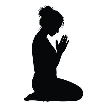 Silhouette of a woman praying on her knees with her hands together in a gesture of worship or supplication 