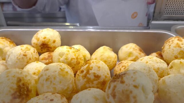 Server picking up several steaming cheese puffs showing off their texture and crispiness.