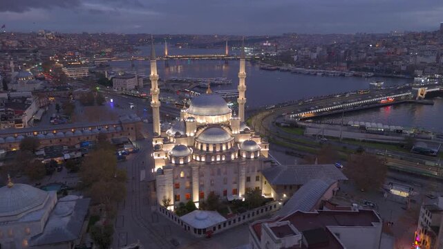Aerial drone view of Istanbul historic Golden Horn, showing the Eminonu New Mosque or Yeni Cami, Galata Bridge, and Bosphorus at sunrise or sunset. Topkapi Palace and Hagia Sophia in the distance.