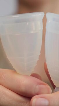 Close-up woman shows menstrual cup in hand. Feminine hygiene products, gynecology and self-awareness. Daily care and the female cycle. Eco in women health, menstruation or period