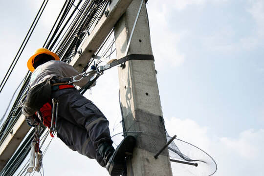 Electricians work on utility poles with safety as their top priority.