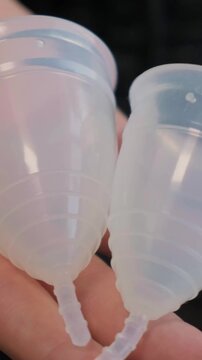 Close-up woman shows menstrual cup in hand. Feminine hygiene products, gynecology and self-awareness. Daily care and the female cycle. Eco in women health, menstruation or period