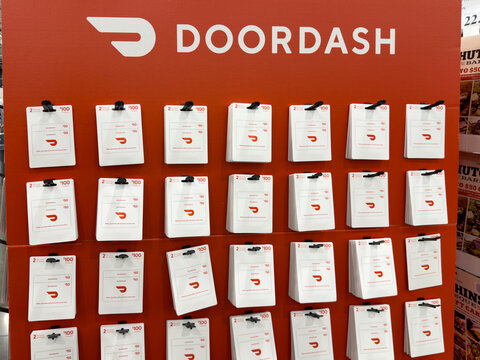DoorDash gift cards worth one hundred dollars each hanging on red branded cardboard