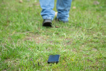 Smartphone on green grass in the park. Lost phone