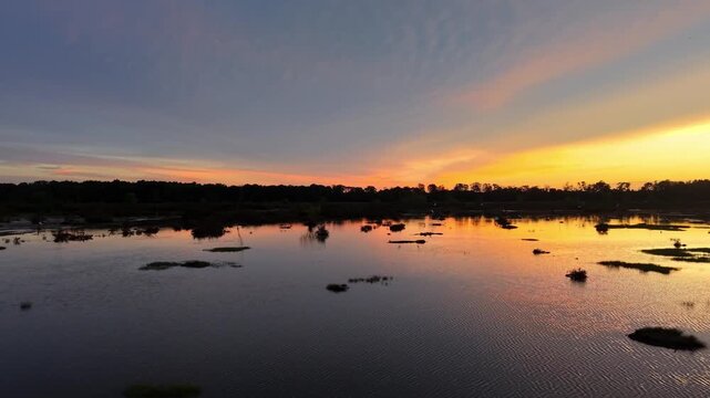 Drone view highlights Pulau Aman surrounded by shimmering waters under vibrant orange sunset glow.