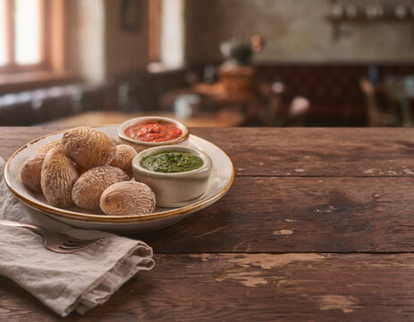 Traditional Canarian wrinkled potatoes with red and green mojo sauce on a rustic dark oak table in a cozy restaurant, natural side lighting and large copy space for design