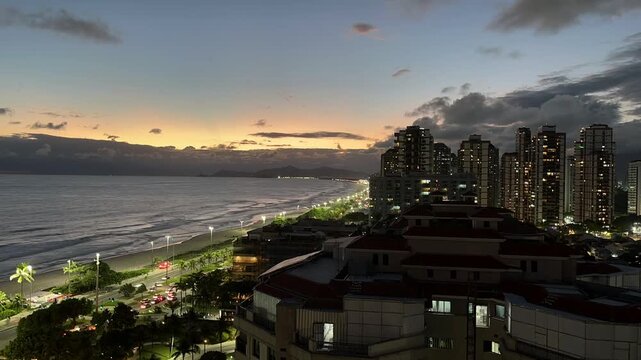 Time-Lapsed nightfall over beachfront avenue and clouds drifting in the wind, modern high-rise buildings lock down camera full shot in Barra Tijuca, Rio de Janeiro lock down camera full shot