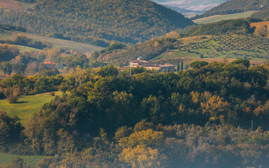 Obraz premium Tuscan hills covering autumn trees and country villas, Italy.