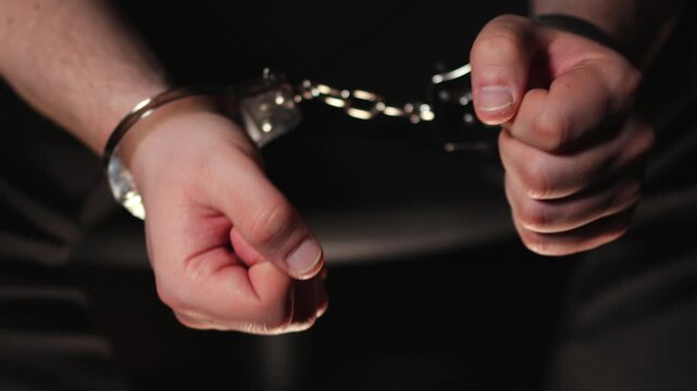 a man's wrists. Steel handcuffs. A man in handcuffs. Slow motion video. High quality 4k footage