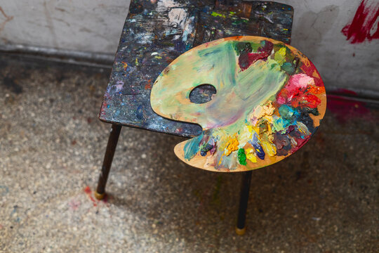  A palette of oil paints lies on an old chair. Photographs of art objects. 