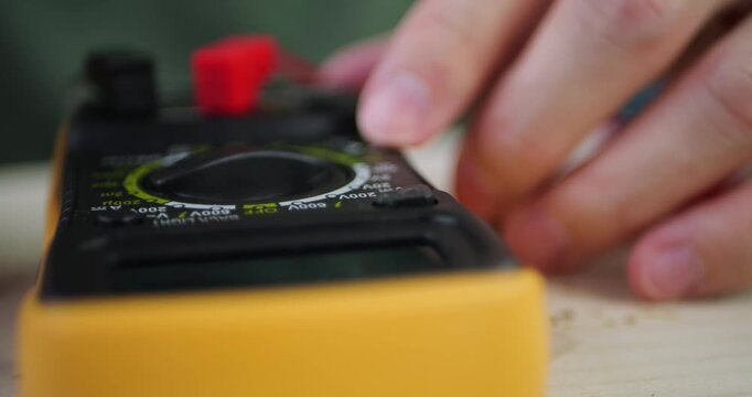 Hands adjust multimeter settings for precise measurements. Technological device aids in electrical testing and diagnostics. Scene captures focus and concentration of individual. Ideal for educational