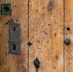 Cotignac, Provence-Alpes-Côte d’Azur, France : close-up of old wooden door with vintage locks and metal handle, rustic texture background with copy space