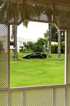 Black Lamborghini Gallardo side view framed by lattice, Exclusive sports car parked on estate lawn