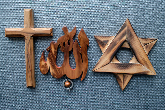 Three Abrahamic religion. Interreligious harmony shown through wood-carved cross, Allah pendant, and Star of David.