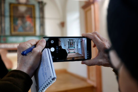 Baroque chapel of Bonnay. Woman with colorful bracelet photographs the restored retable on her mobile phone.  Saint Gervais.  France.