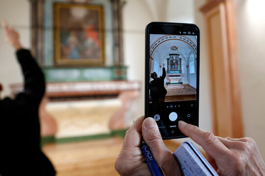 Baroque chapel of Bonnay. Woman with colorful bracelet photographs the restored retable on her mobile phone.  Saint Gervais.  France.