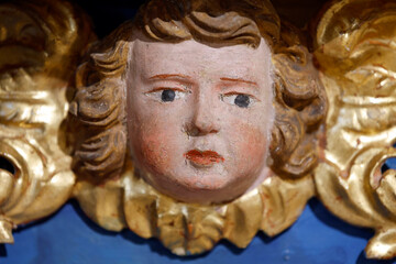 Fototapeta premium Baroque chapel of La Gruvaz after restoration. Carved angel head emerges from ornate golden frame of the chapel retable. Saint Gervais. France.