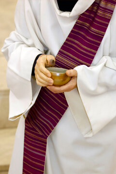 Saint Paul church. Close-up of deacon's hands holding ceramic ash bowl at Ash Wednesday liturgical ceremony. Annecy. France.