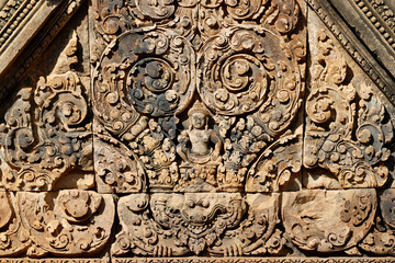 Obraz premium Sunlit carvings on Banteay Srei sanctuary doorway reveal guardians, foliage motifs, and legendary scenes in exquisite detail. Siem Reap. Cambodia.