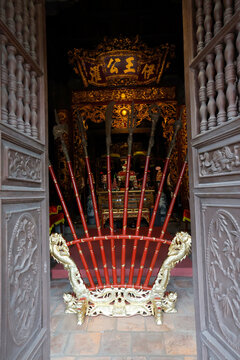 Communal house dedicated to national hero Ngo Quyen.Red lacquered ceremonial pole weapons fan out before a richly decorated temple. Haiphong. Vietnam.