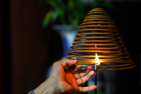 Pho Chieu Buddhist temple. Close-up of a hand lighting a spiral incense coil.  Haiphong. Vietnam.