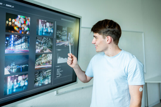Teen boy presenting school project in front of classroom.