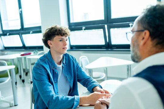 Teacher supporting struggling student with learning difficulties during lesson.