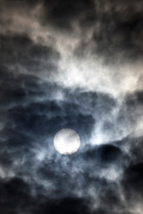 Fototapeta premium Sun pierces thick swirling clouds, golden glow amid dramatic daytime stormy sky layers. Bor et Bar. France.