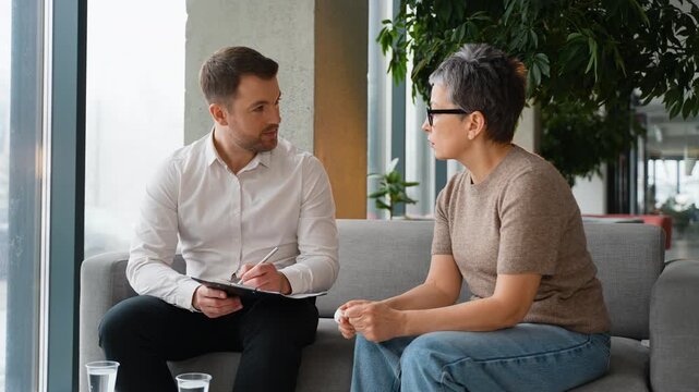 Psychologist taking notes during therapy session with patient