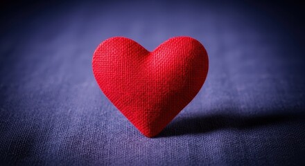 Obraz premium A vibrant, handcrafted textured red heart object placed centrally on a rustic, folded dark indigo fabric surface, background, object, deep